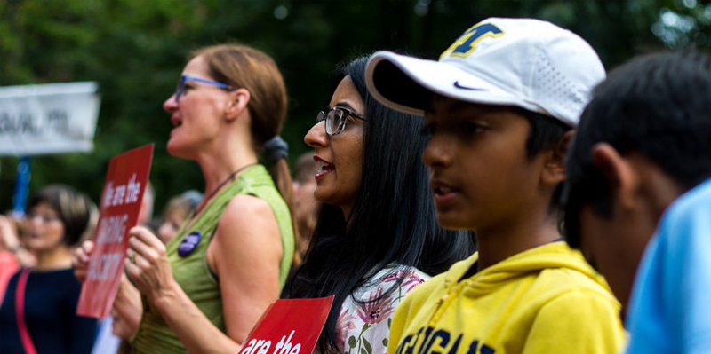 Activists of various ages and races hold signs at a rally.