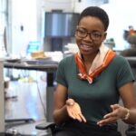 Victoria, a Black woman with short hair wearing glasses, speaks to someone out of frame