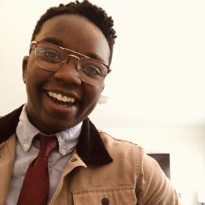 Shanté, a Black woman with short hair and glasses, faces the camera flashing a big smile