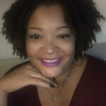 A headshot of Aisha, a Black woman with short curly hair and purple lipstick