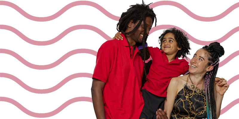 A family of three with a range of skin tones, including two adults and a young child, smile with their arms around each other.