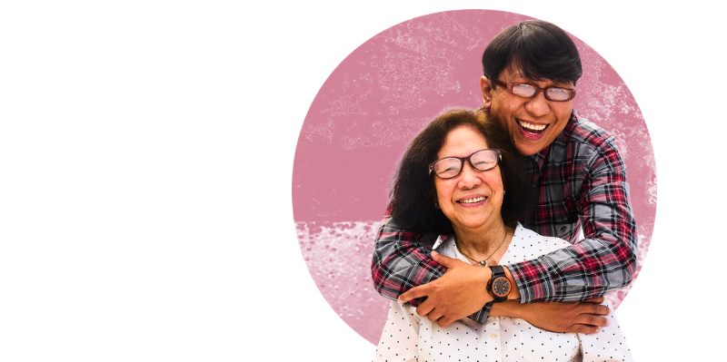 Image shows a man hugging his mother against a pink background